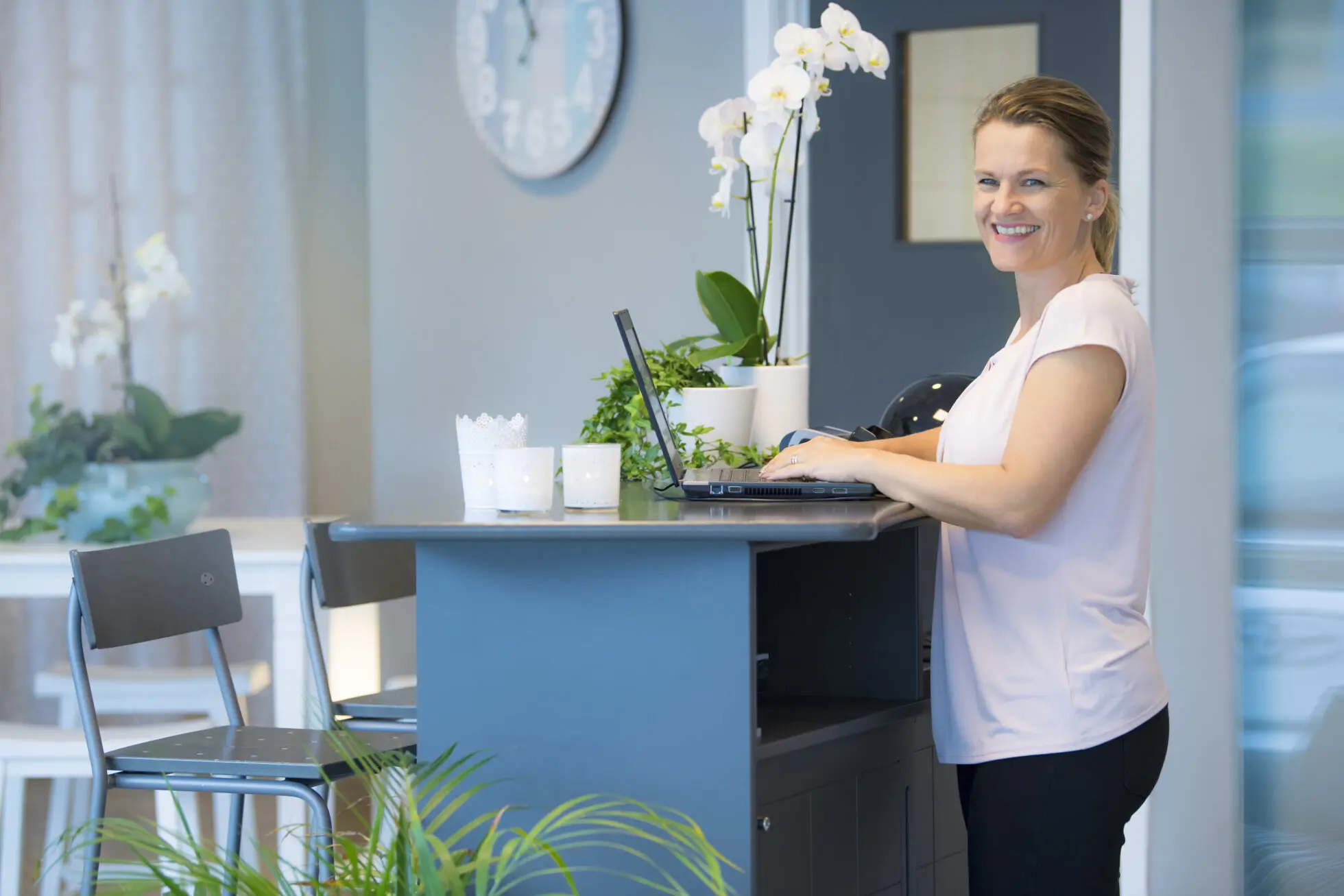 Bildet viser en dame som står ved en PC